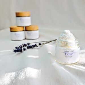Lavender Face cream in the sunshine and 3 jars behind with three lavender stems between